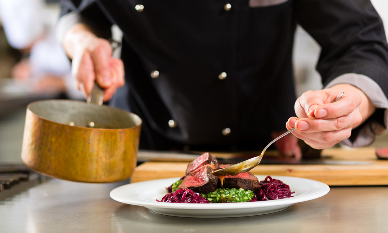 Cuisinier qui dresse une assiette pendant le service d'un restaurant