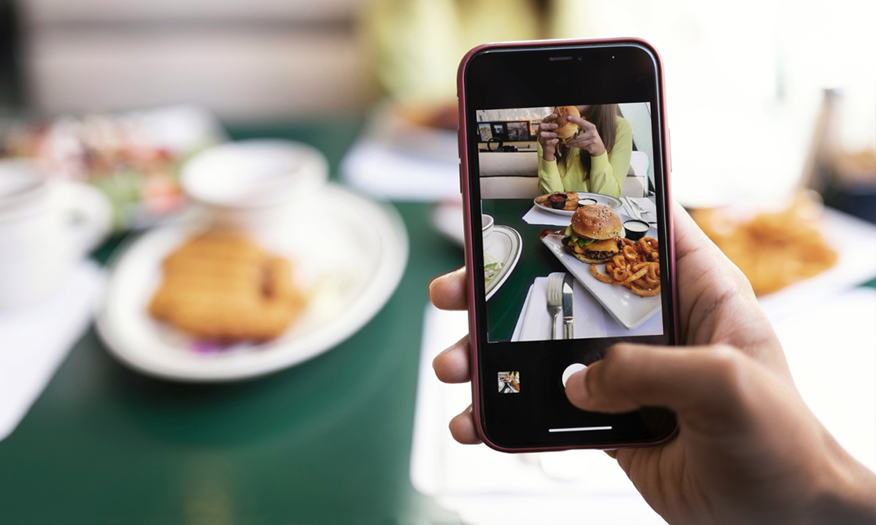 Client qui prend en photo un plat avec son smartphone dans un concept de restauration rapide