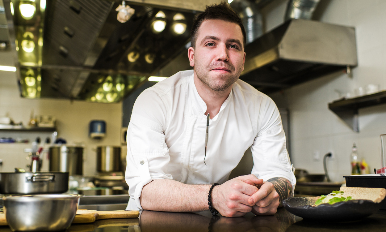 Portrait d'un cuisinier qui pose fièrement dans a cuisine