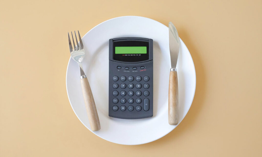 Une calculatrice posée dans une assiette avec des couverts