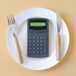 Une calculatrice posée dans une assiette avec des couverts